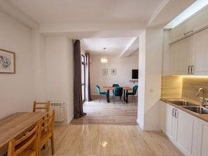 A modern kitchen with white cabinets, a wooden countertop, and a stainless steel sink. - Bright Stylish 2BR Escape in Charming Vera (T`bilisi)