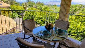 Ein Balkon mit Tisch für zwei Personen, Stühlen, einer Obstschale und Blick auf Grünflächen und Berge.