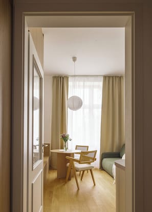 Ein Flur, der in einen Essbereich mit Tisch, Stühlen, einem Blumenstrauß und einer Pendelleuchte führt.