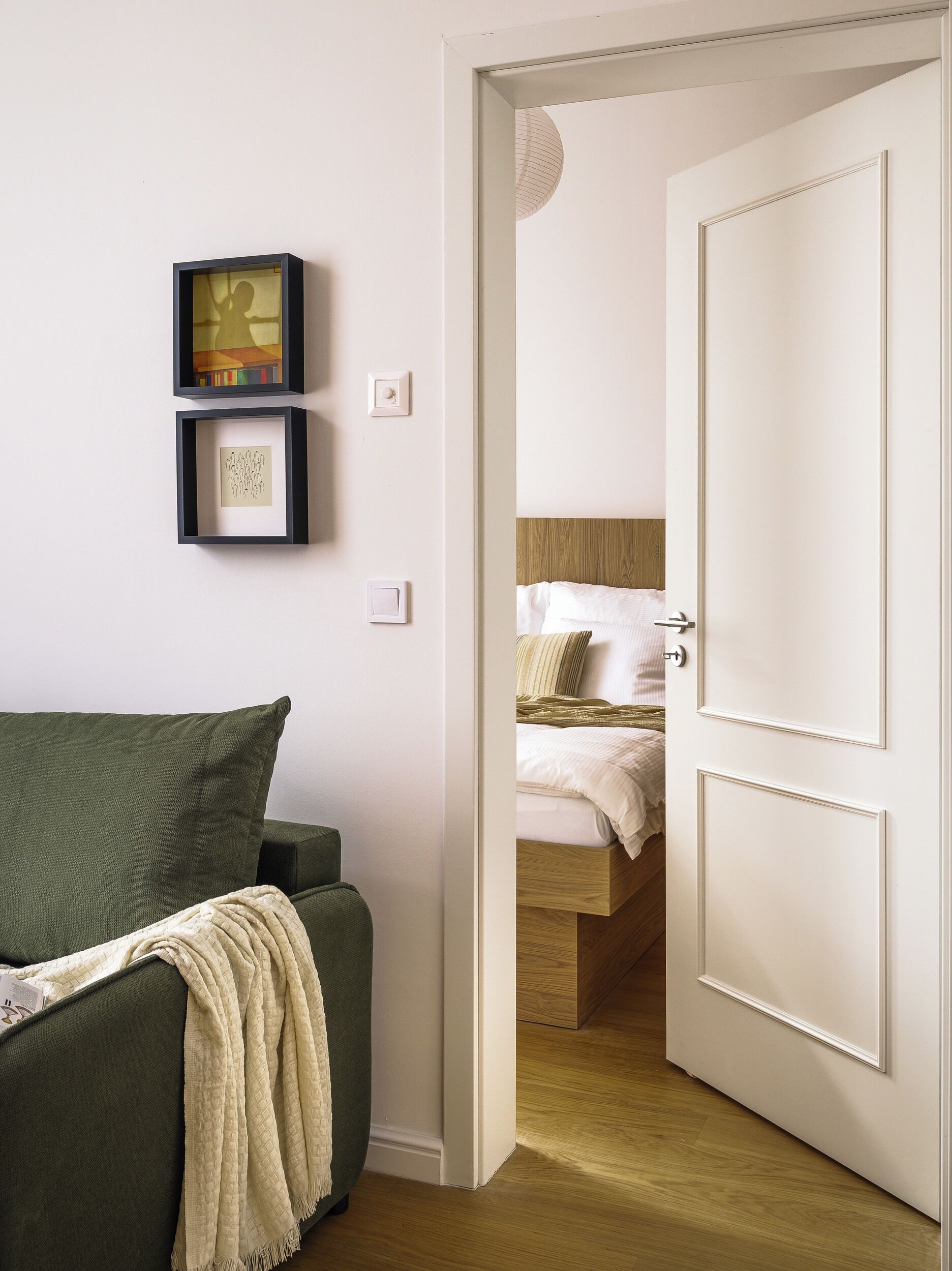 A room with a bed, a green sofa, and a door leading to another room.