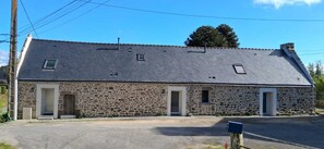Un edificio de piedra con techo inclinado, dos puertas y ventanas pequeñas.