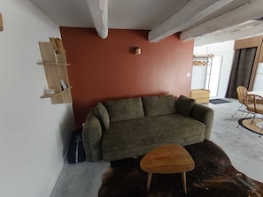 A living room with a sofa, a small wooden table, a leather rug, and a wall-mounted shelf. - Newly renovated apartment in beautiful farmhouse with south-facing terrace. Pets allowed (Merlevenez)