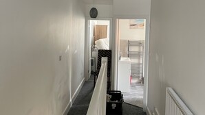Ein Flur mit Treppe, Heizkörper und einer Tür zu einem anderen Raum.
