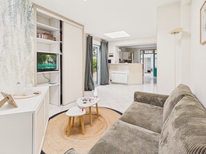 A modern living room with a sofa, a television, a small table with a rug, and a bookshelf. - 650 m from the beach, charming house for 4 people (Dinard)