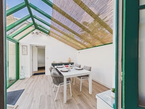A dining area with a table set for four, a green-framed window, and a woven ceiling. - 650 m from the beach, charming house for 4 people (Dinard)
