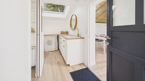 Un bagno moderno con un lucernario, uno specchio rotondo e un mobile lavabo bianco.