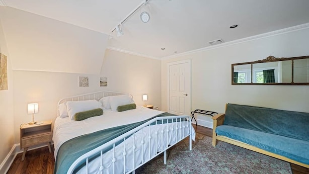 A bedroom with a bed, bedside tables, a sofa, a patterned rug, and a mirror on the wall. - Huntington Village House 4BR – Walk to everything (Huntington)