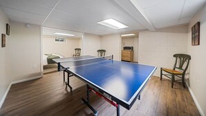 A ping pong table in a room with wooden flooring, white walls, and a ceiling with fluorescent lighting. - Huntington Village House 4BR – Walk to everything (Huntington)