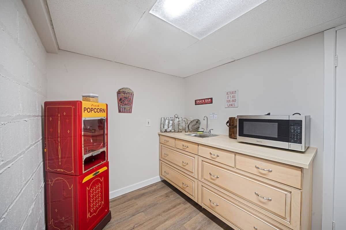 A kitchenette with a microwave, a red popcorn vending machine, and a snack bar sign.