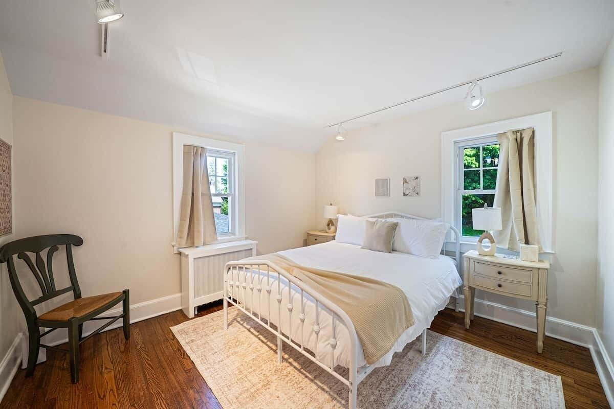 Ein Schlafzimmer mit einem Bett, Nachttischen, einem Sessel und einem Fenster.