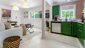 A modern kitchen with green cabinets, a dining area with a sofa and table, and a living room with a sofa and decorative items. - World Cup | .4 Mi to Ponce | 3 Mi to Mercedes Benz (Atlanta)