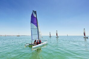 Ein Segelboot mit zwei Personen auf dem Wasser, umgeben von weiteren Segelbooten.