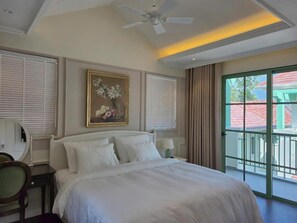 Una camera d'albergo con un letto, una ventola a soffitto, un quadro, una finestra con tende e vista all'esterno.