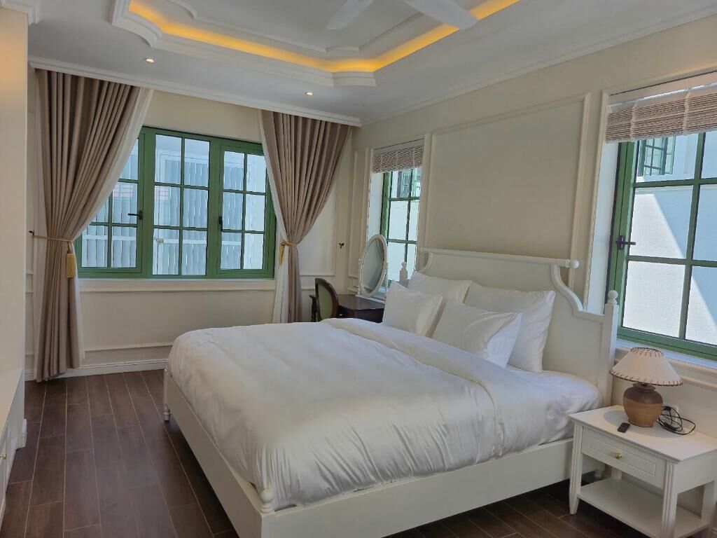 A bedroom with a bed, nightstand, lamp, and curtains.