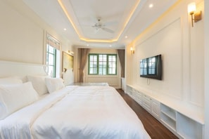 Una camera d'albergo con un letto grande, una televisione a muro e una ventola a soffitto.