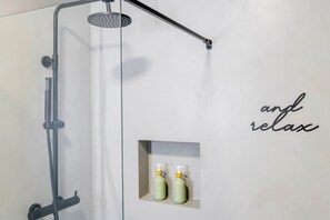 Ein modernes Badezimmer mit Dusche, Handtuchhalter und zwei Shampooflaschen.