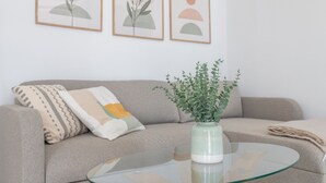Un saló amb un sofà, una taula de centre de vidre i un botic amb una planta.