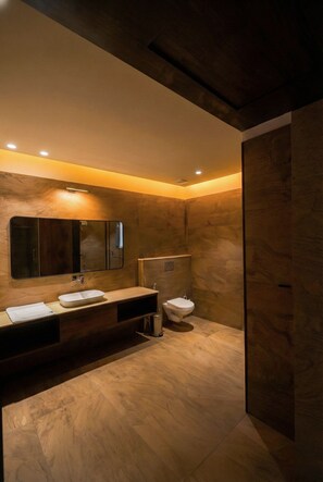 A modern bathroom with a large mirror, a sink, and a toilet.