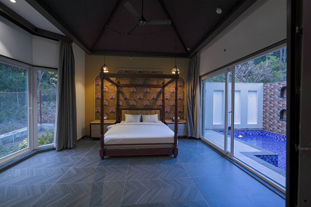 A bedroom with a four-poster bed, large windows, and a view of a swimming pool.