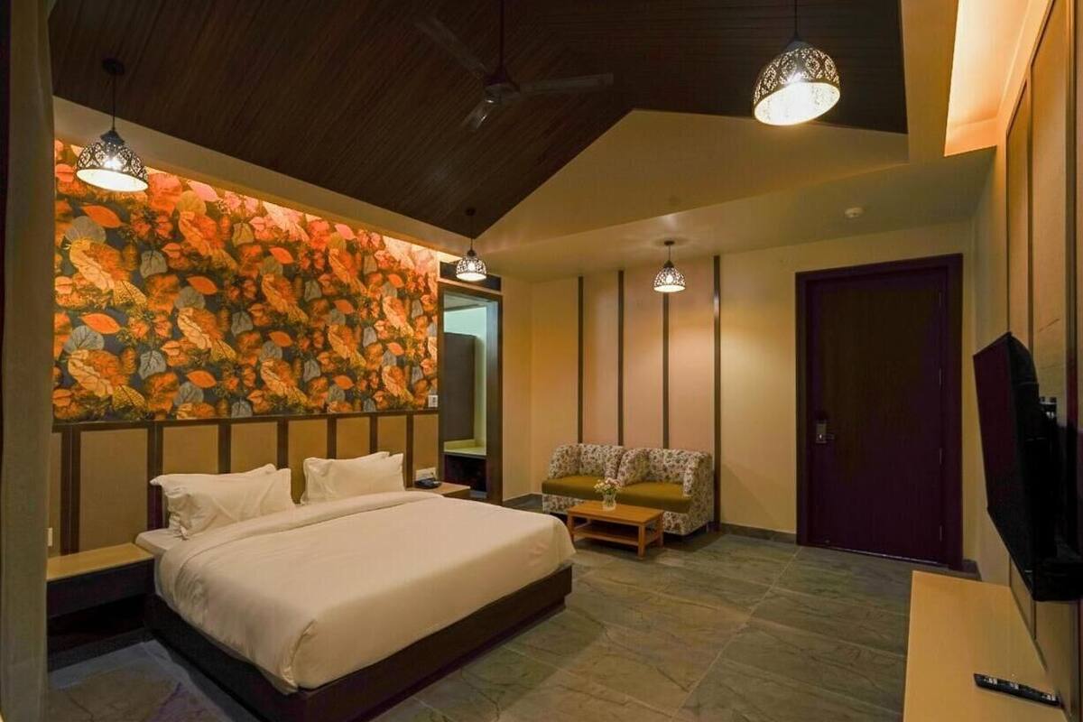 A bedroom with a bed, a sofa, a TV, and a decorative wall.