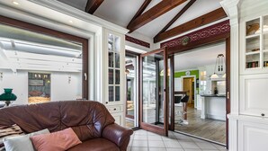 Un vaste salon doté d’un canapé en cuir, d’un coin repas et d’une cuisine visible à travers des portes vitrées.
