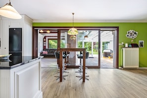 Une cuisine moderne avec un coin repas, un plancher en bois et une vue dégagée grâce à des portes vitrées.