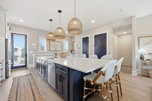 A modern kitchen with a large island, pendant lights, and a view to the outside. - Just Baskin- Walking Distance-Downtown Morehead City (Morehead City)