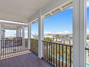 A covered balcony with a view of a swimming pool and buildings. - Lazy Salty Beach | 500ft to Beach + Private Pool, Gulf Views (Panama City Beach)
