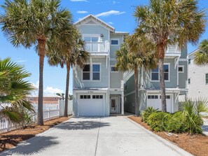 A multi-story residential building with a white facade, a visible garage door, and a clear sky. - Lazy Salty Beach | 500ft to Beach + Private Pool, Gulf Views (Panama City Beach)