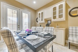 A dining area with a black table, white chairs, and a buffet cabinet.