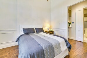 A neatly made bed with a striped bedspread, a bedside lamp, and a small nightstand with a vase of flowers.