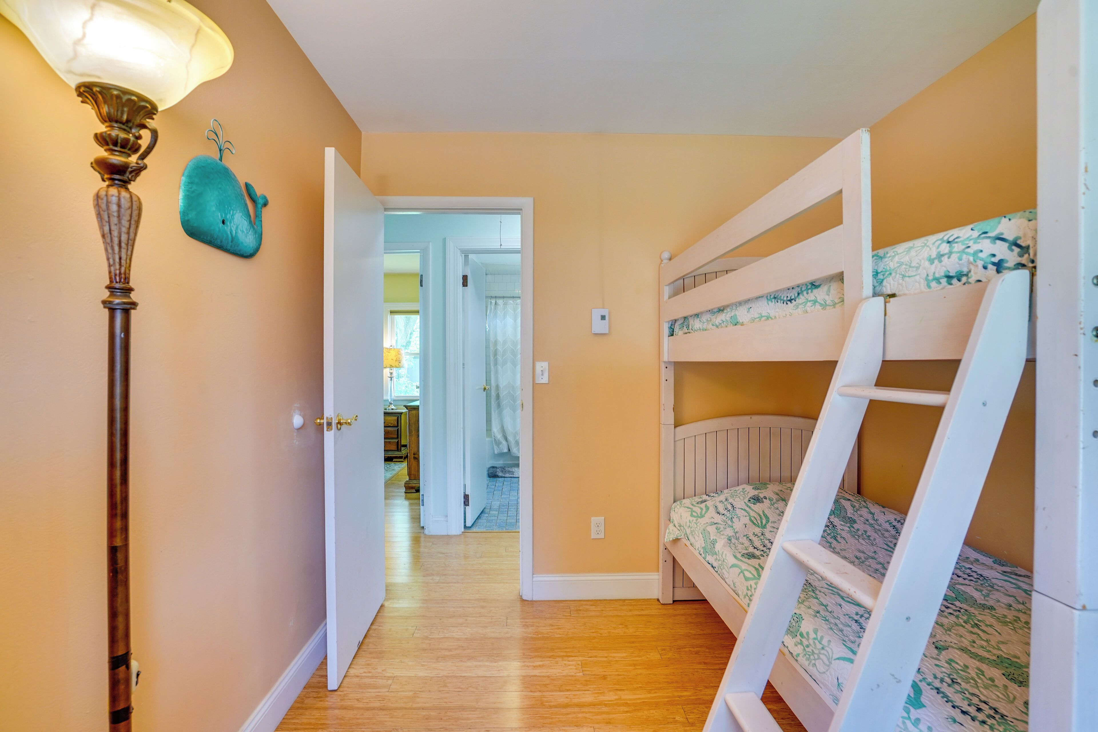 A room with a bunk bed, a lamp, and a door leading to another room.