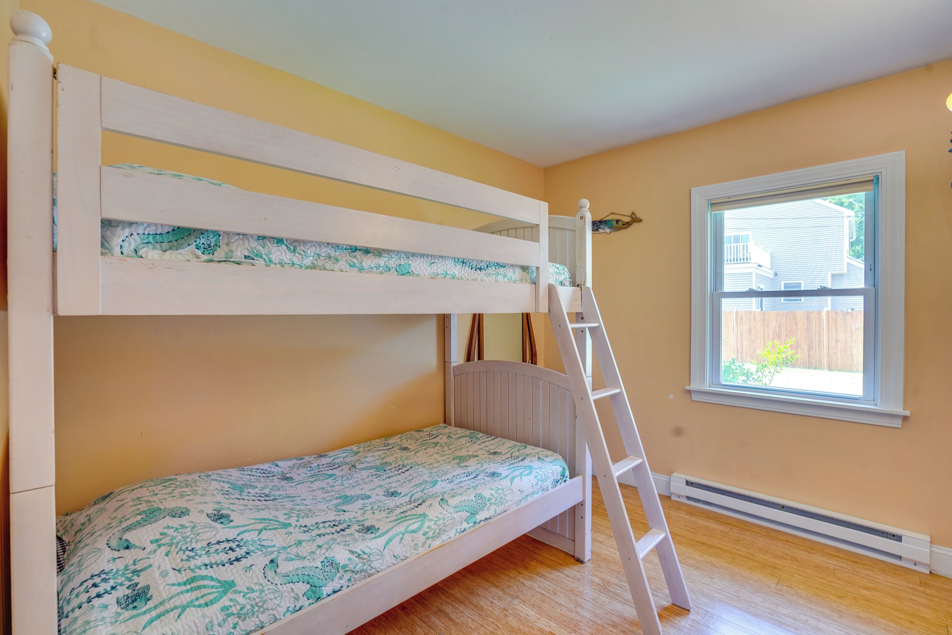 A bunk bed with a ladder, a window with a view, and a radiator.