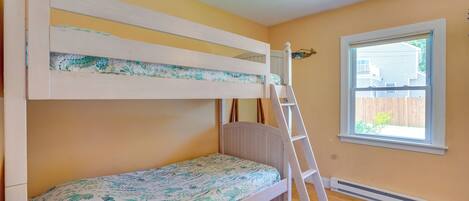 A bunk bed with a ladder, a window with a view, and a radiator.