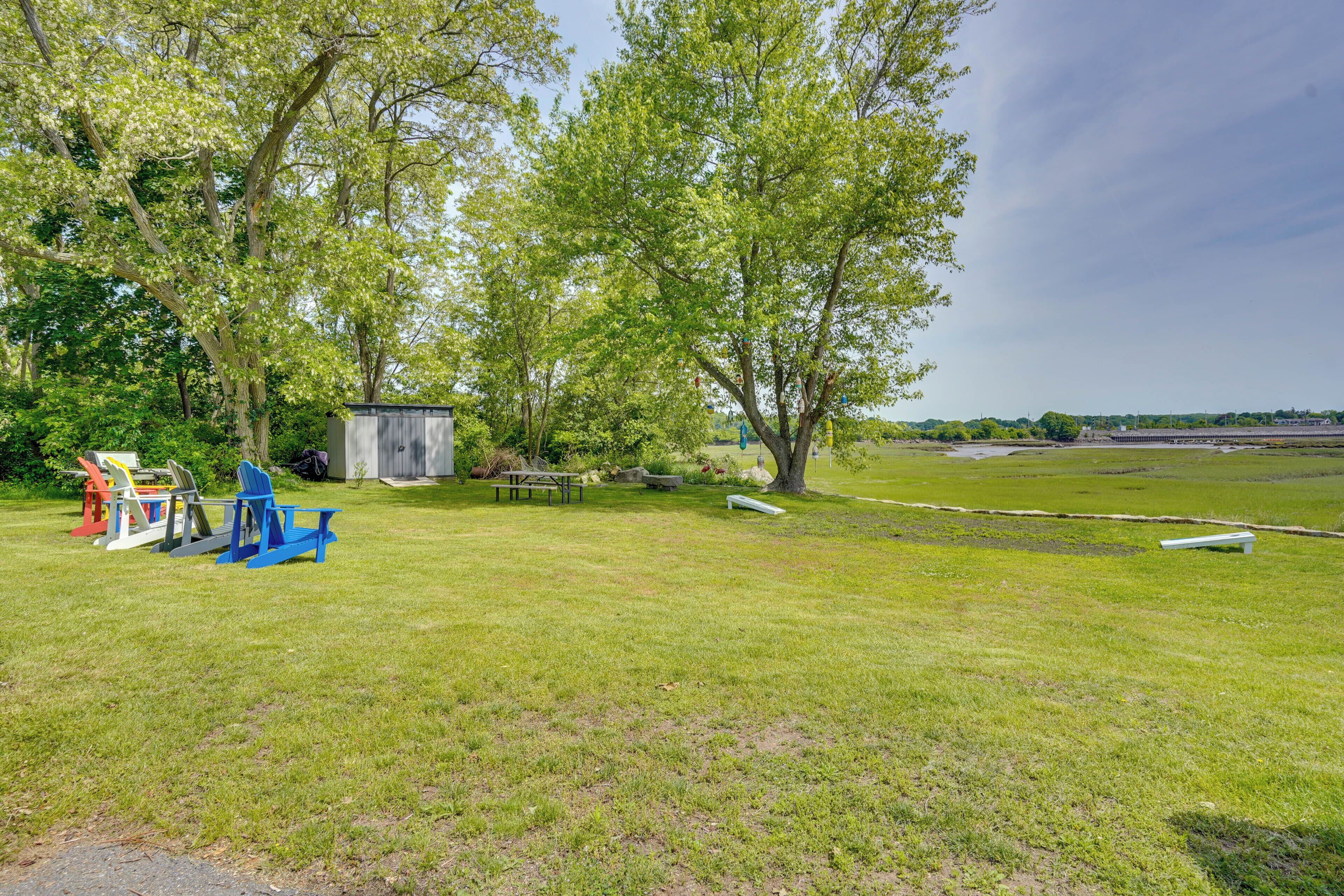 A grassy outdoor area with trees, a small shed, and a bench.