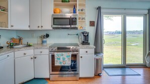 A kitchen with white cabinets, a stainless steel oven, a microwave, and a coffee maker. - Lovely 'the Buoys Cottage' on Annisquam River! (Gloucester)