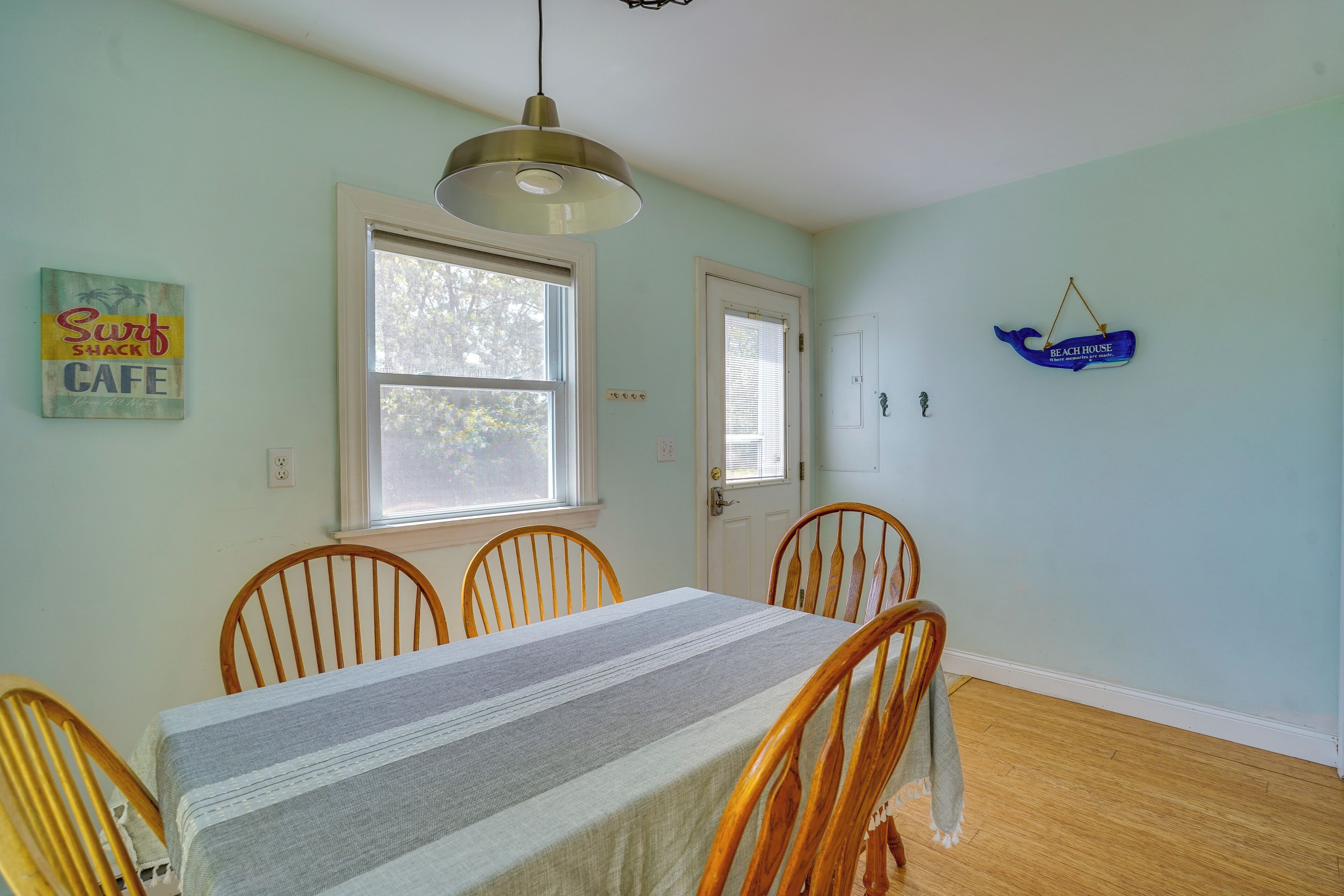 A dining area with a table, chairs, a hanging light fixture, and a door with a window.