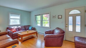 A living room with a brown leather sofa, a wooden coffee table, and a door with decorative glass panels. - Lovely 'the Buoys Cottage' on Annisquam River! (Gloucester)