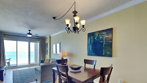 Un espace repas comprenant une table, des chaises, un lustre et un tableau accroché au mur.