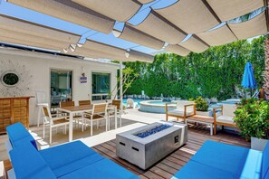 An outdoor patio with wooden furniture, a fire pit, and a pool area. - Putting Green & Outdoor Lounge! Palm Springs Home (Palm Springs)