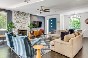 A modern living room with a stone accent wall, a fireplace, a sofa, a coffee table, and a TV. - Putting Green & Outdoor Lounge! Palm Springs Home (Palm Springs)