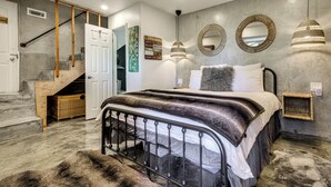 Une chambre à coucher avec un lit, un escalier et un miroir fixé au mur.