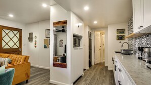 Une cuisine moderne avec des armoires blanches, un comptoir en marbre et un ventilateur de plafond en bois.