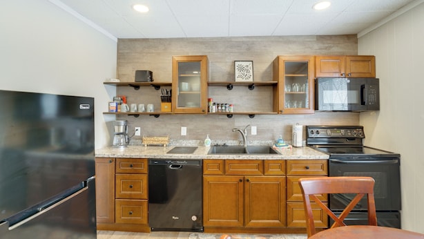 A kitchen with wooden cabinets, a dishwasher, a refrigerator, a microwave, and an oven. - Easy Lake Access! Blue Water Base Camp Near Dtwn (Port Huron)