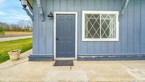 A house with a blue door, a window with a diamond pattern, and a small porch with a potted plant. - Easy Lake Access! Blue Water Base Camp Near Dtwn (Port Huron)