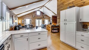 A spacious kitchen with white cabinetry, a dining area with a table and chairs, and a wooden ceiling. - Game Room, Dock & More! Panoramic Lakefront Oasis (Six Mile)