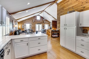 A spacious kitchen with white cabinetry, a dining area with a table and chairs, and a wooden ceiling. - Game Room, Dock & More! Panoramic Lakefront Oasis (Six Mile)