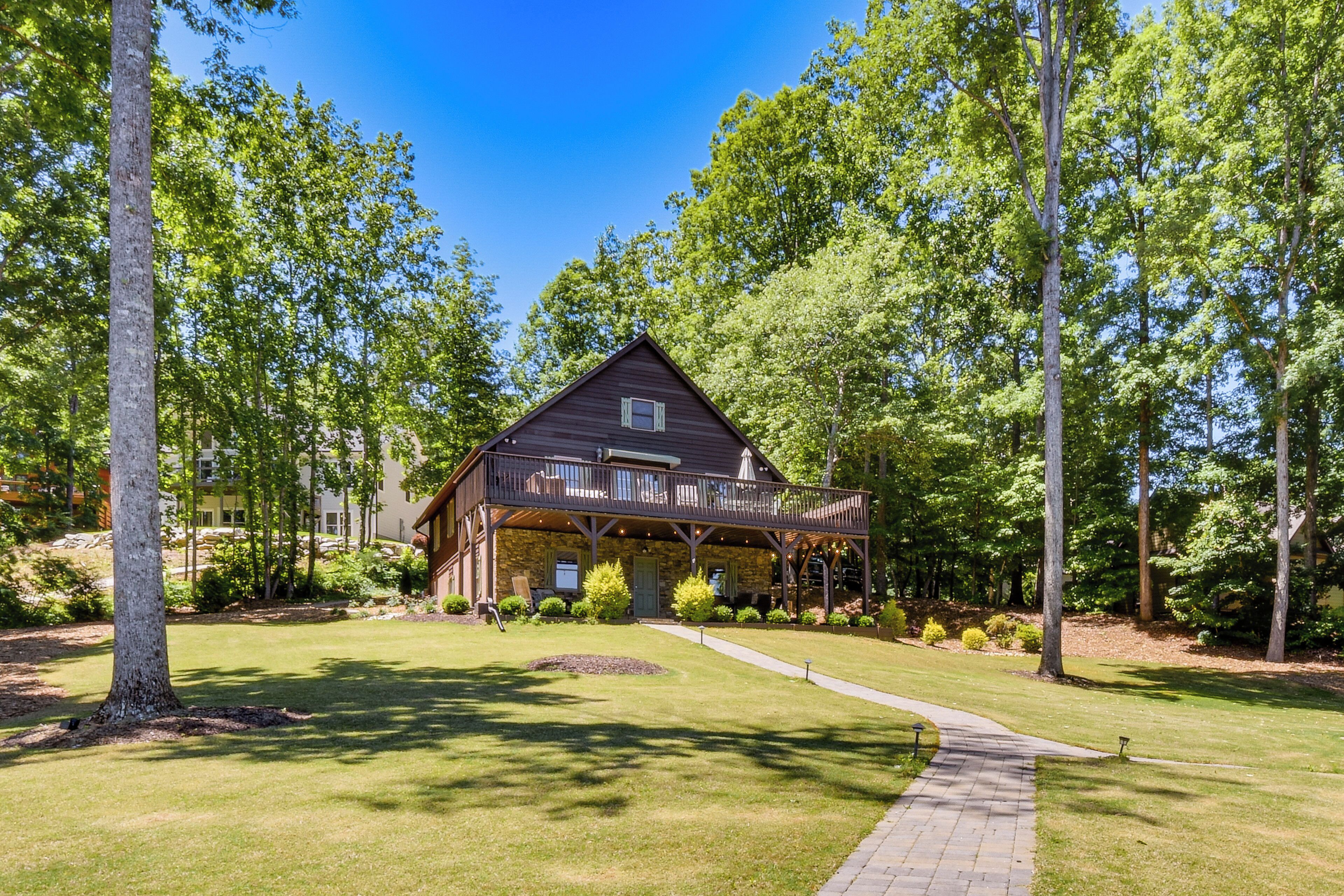 A lodge with a covered porch, surrounded by trees and a well-maintained lawn.