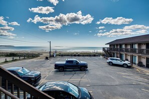 A parking lot with a building, a view of the ocean, and a clear sky. - Beachfront Condotel on Oob, Steps From Downtown (Old Orchard Beach)
