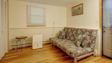 A small living room with a sofa, a radiator, a table, and a door.